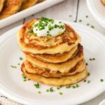 A stack of pancakes with sour cream and chives.