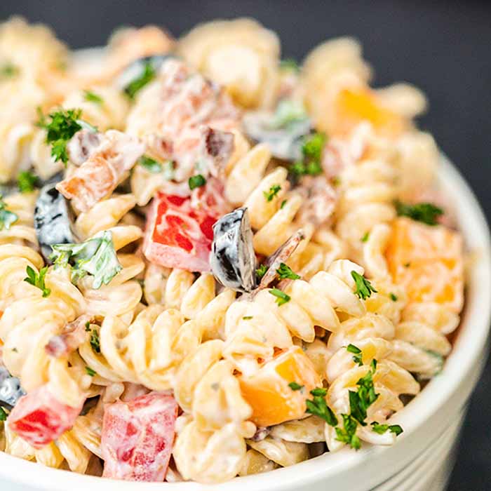 A white bowl full of bacon ranch pasta salad in it. 