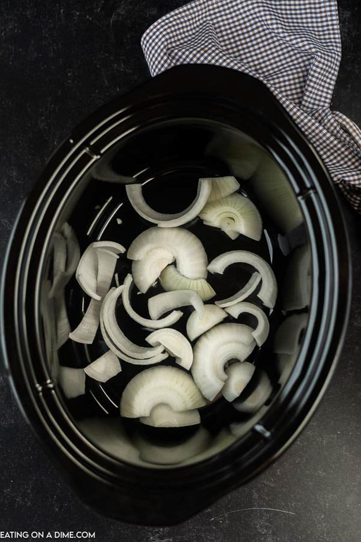 Placing chopped onions in the slow cooker
