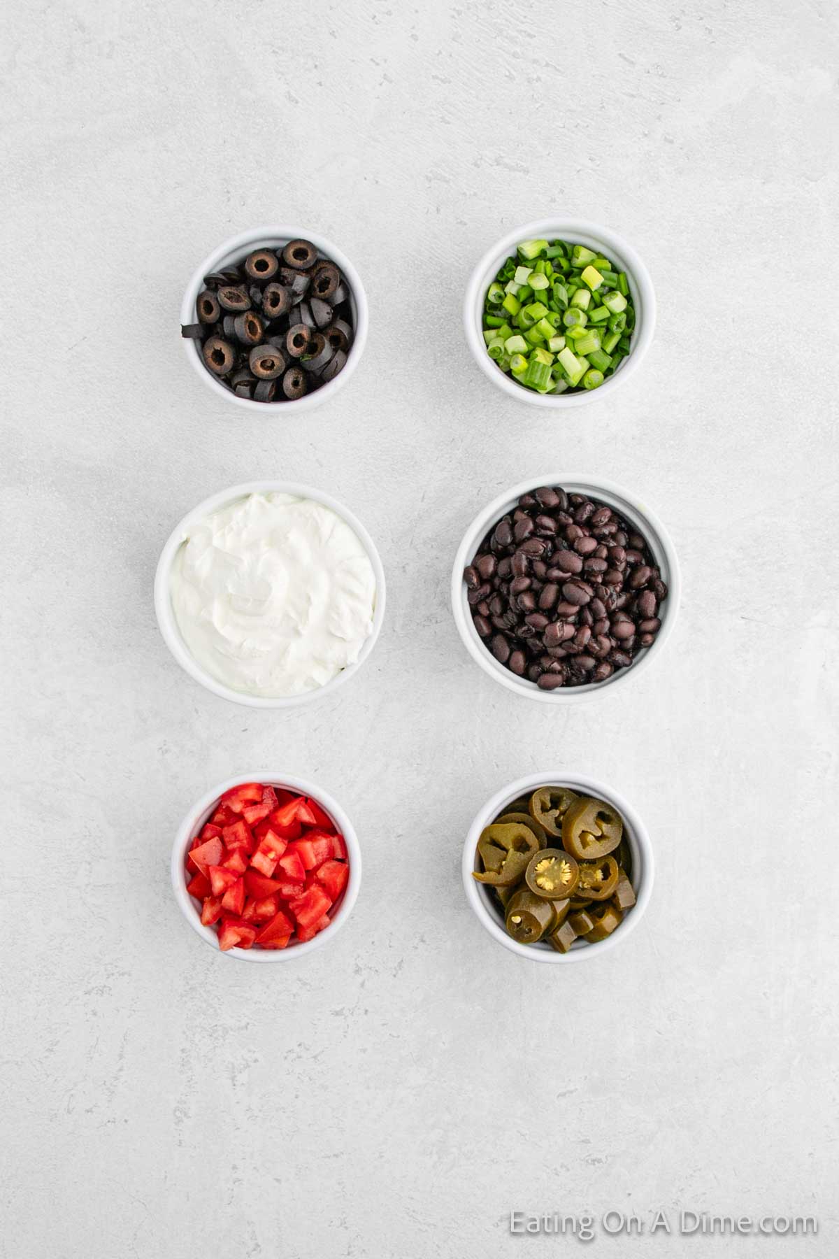 Bowls of black olives, sour cream, diced tomatoes, Green onions, black beans, slice jalapenos