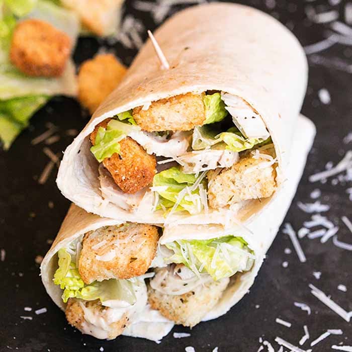 Chicken Caesar Salad Wrap recipe is a quick meal idea that includes everything you love about Caesar Salad. This grab and go wrap can be ready in 5 minutes for an easy lunch or dinner. Chicken Caesar Wraps are healthy and we show you the best way to prepare them. #Eatingonadime #chickencaesarsaladwraprecipe