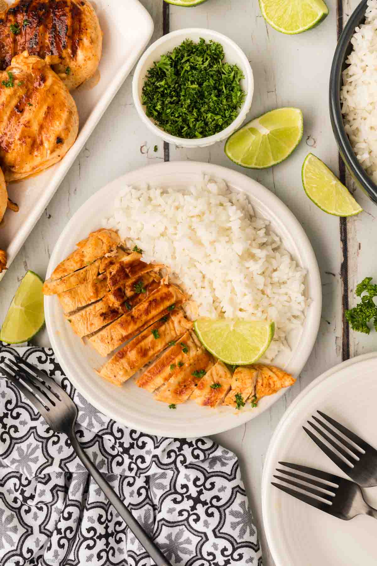 Slice chicken breast on a plate with white rice and lime wedges
