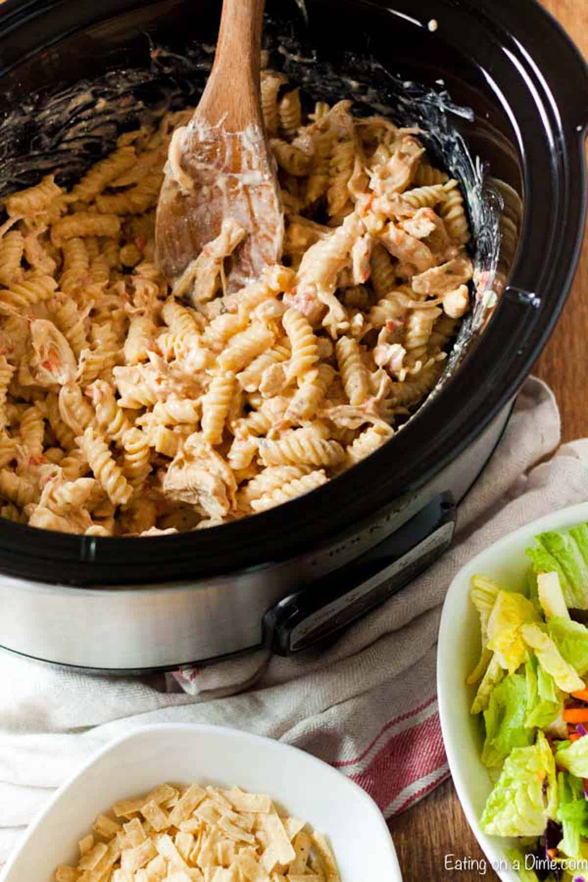 The Creamy Salsa Ranch Chicken Pasta cooked in a crock pot with a serving bowl in the crock pot.  