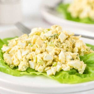 Egg salad on top of lettuce on a plate.