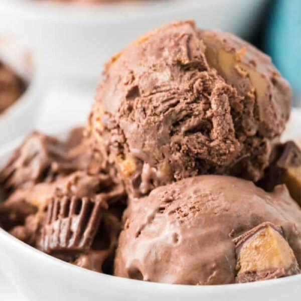 Two scoops of Reese's Peanut Butter Ice Cream with chunks of peanut butter cups in a white bowl.