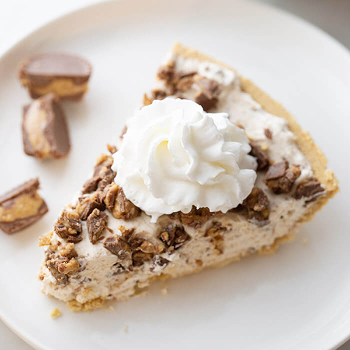 Close up image of Reese's Cup peanut butter pie on a plate. With Reese's Cups on the side. 