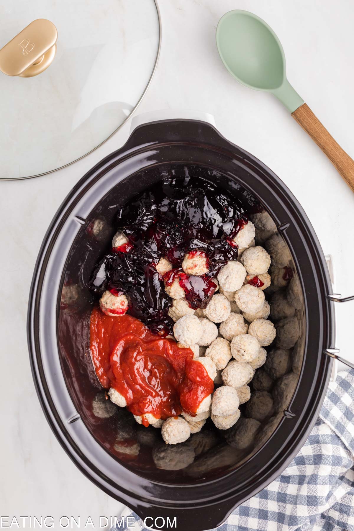 Adding the chili sauce and grape jelly in the crock pot with the meatballs