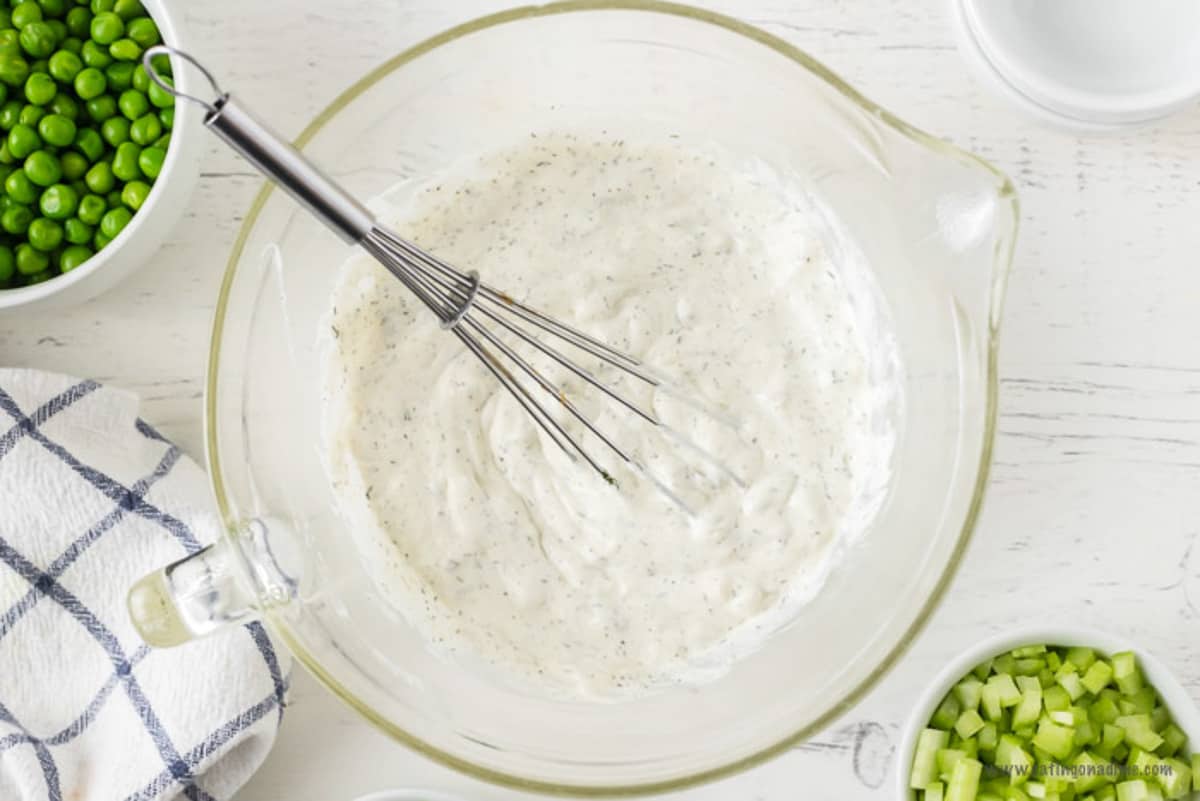 Combining the dressing ingredients in a bowl with a whisk