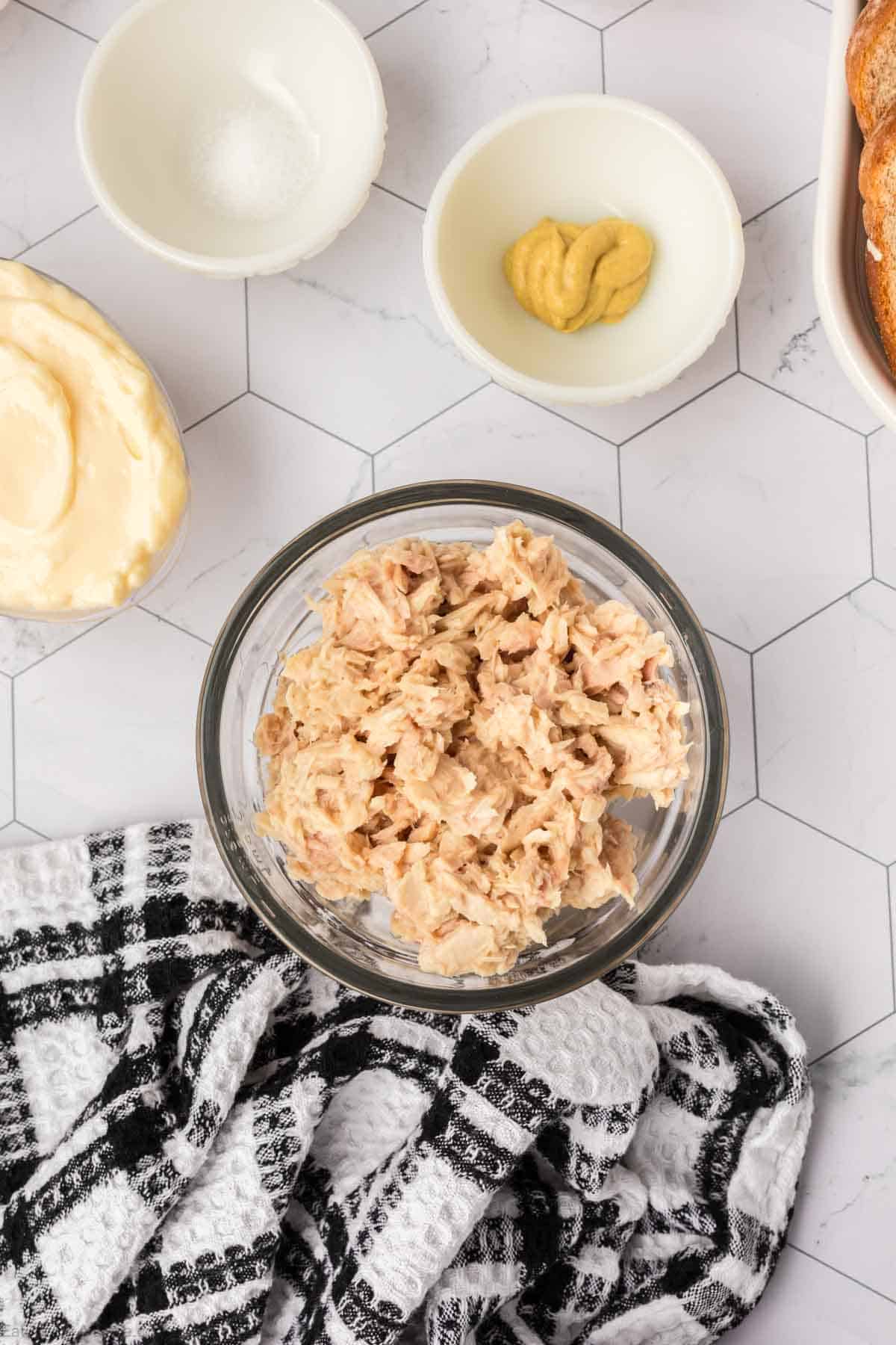 Drained tuna to a bowl with small bowls of mayonnaise and mustard