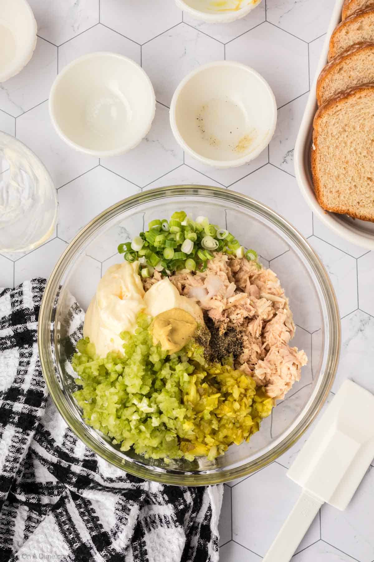 Tuna in a bowl with green onions, mayonnaise, mustard, chopped celery and pickles