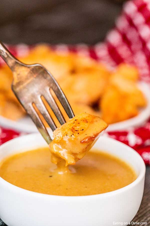 Close up image of chick fil a sauce being dipped with a chicken nugget on a fork.