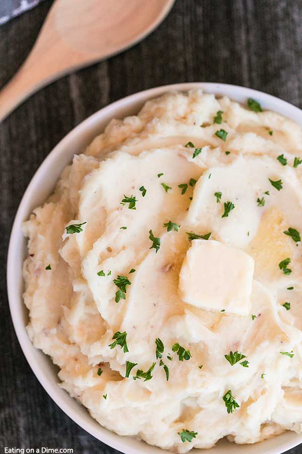A large bowl of mashed potatoes topped with butter 