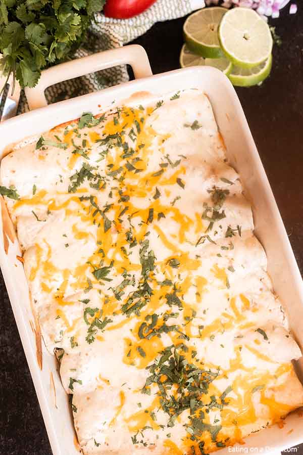 Green Chili Chicken Enchiladas bakes in only 20 minutes for an easy meal for weeknights. From the creamy and easy sour cream sauce to the green chili's, this dish is amazing. If you are looking for the best Mexican enchilada recipe, try this delicious white sauce over flour tortillas. #eatingonadime #greenchilichickenenchiladas #hatch #newmexico
