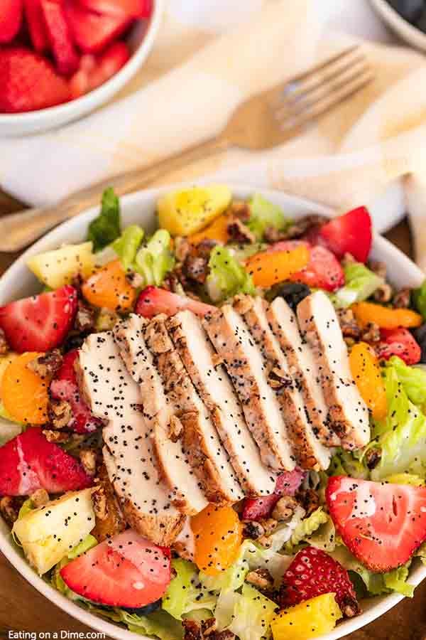 Panera Strawberry Poppyseed Salad is loaded with fruit and tender chicken. Delicious poppyseed dressing drizzled over the salad makes the dish even better. This copycat panera recipe is easy to make. Try this Panera Bread poppyseed salad with chicken today. #eatingonadime #panerastrawberrypoppyseedsalad