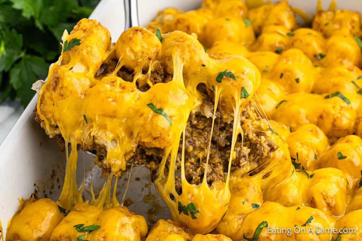 Cheeseburger tatot tot casserole in a baking dish with a serving on a spatula