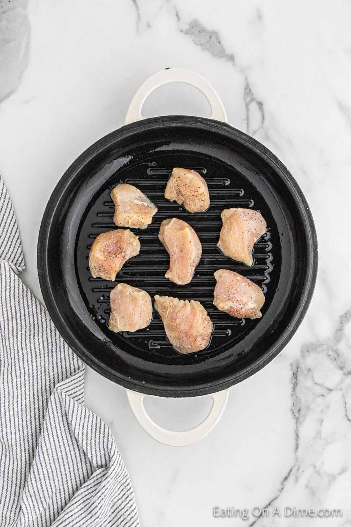 Placing the chicken in a skillet to cook