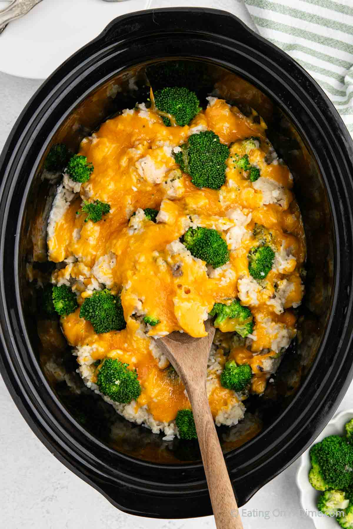Close up image of Chicken Broccoli Rice Casserole in the slow cooker with a serving on a wooden spoon 