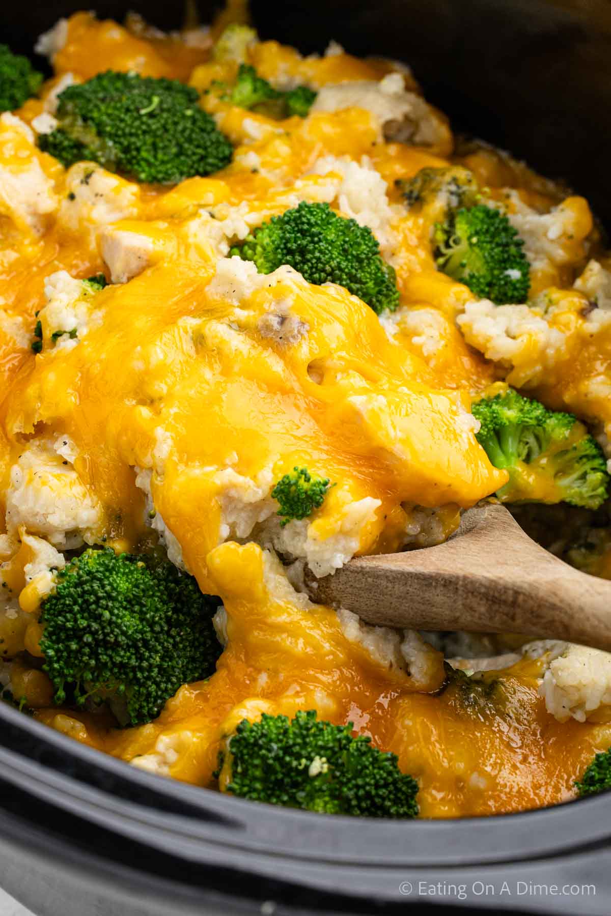 Close up image of Chicken Broccoli Rice Casserole in the slow cooker with a serving on a wooden spoon 