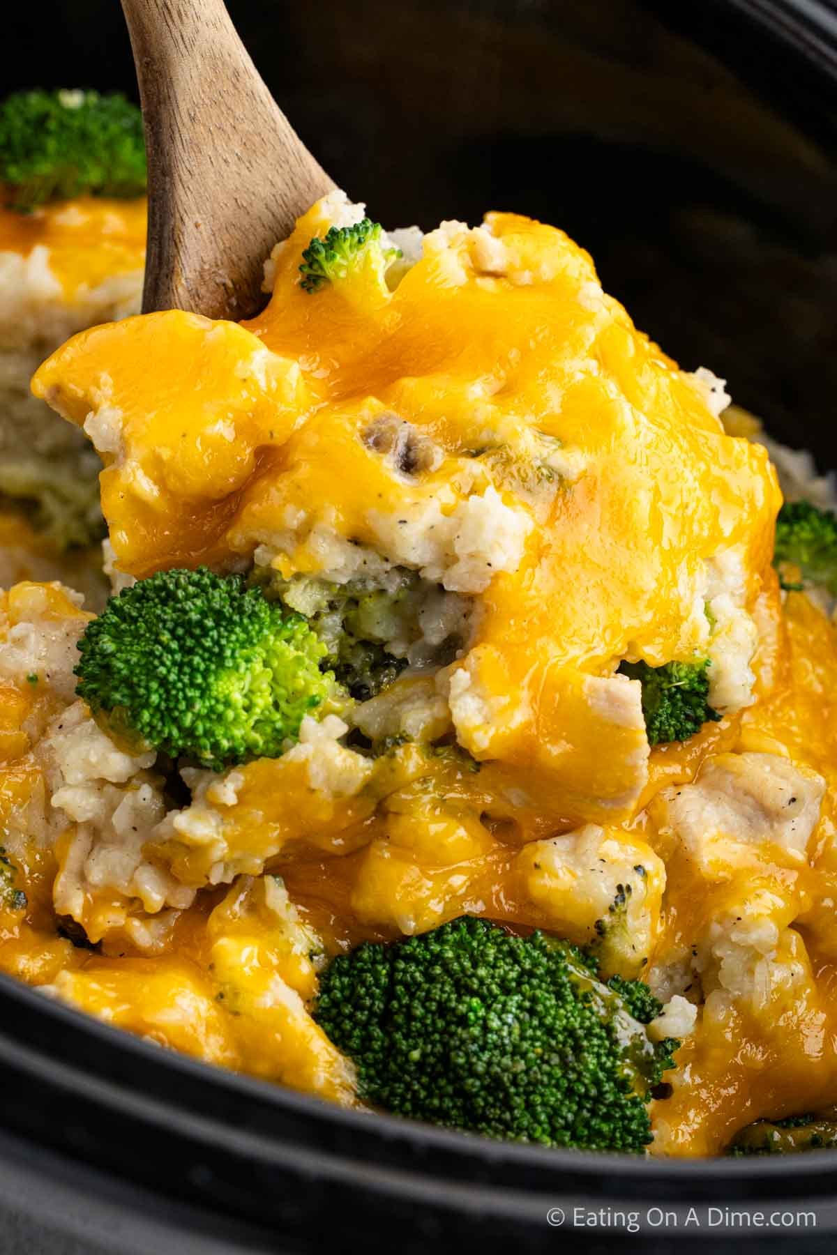 Close up image of Chicken Broccoli Rice Casserole in the slow cooker with a serving on a wooden spoon 