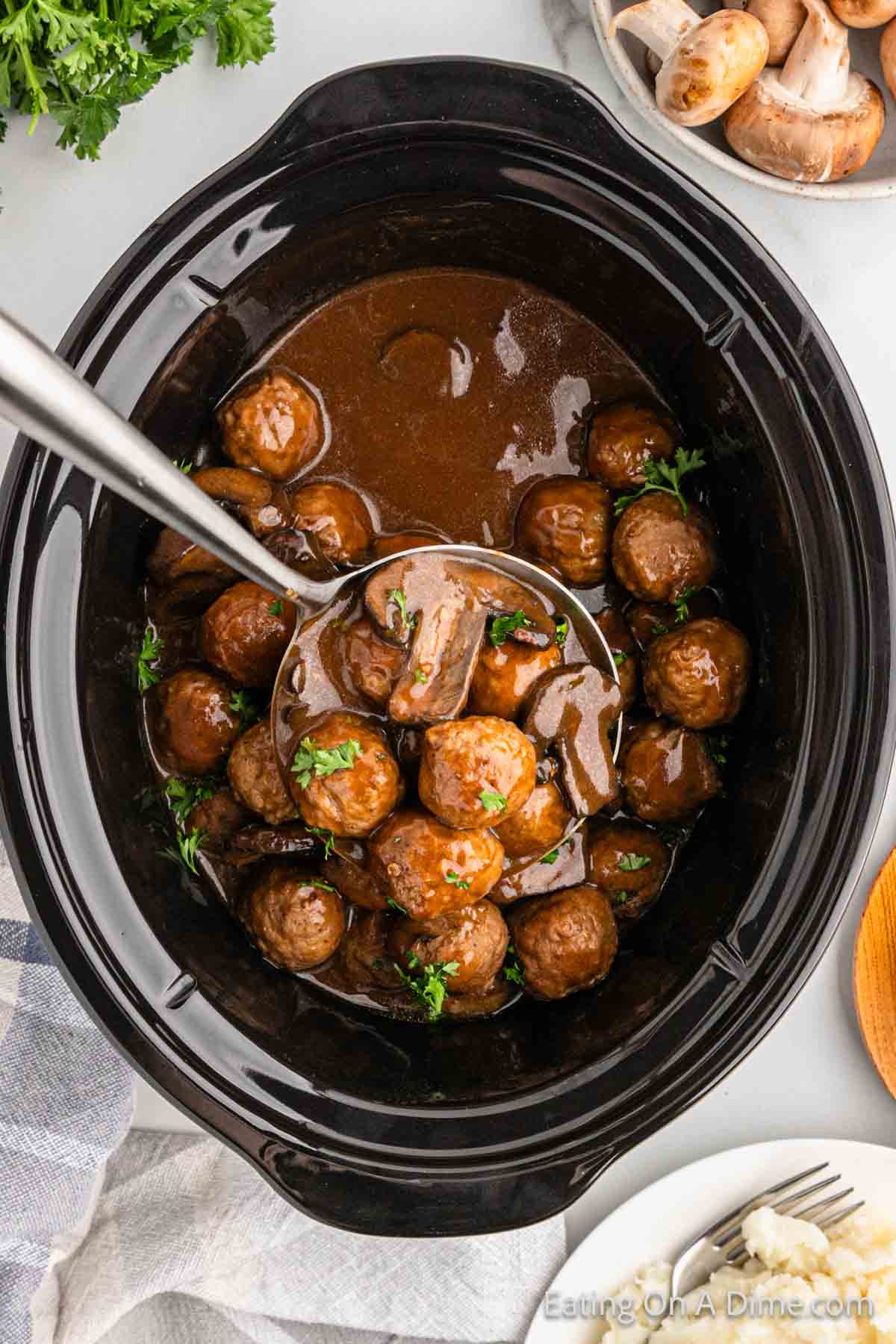 Meatballs in a slow cooker with a serving on a ladle