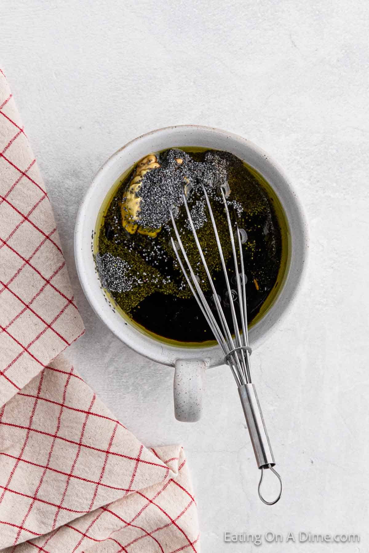 Whisking the salad dressing ingredients in a white bowl