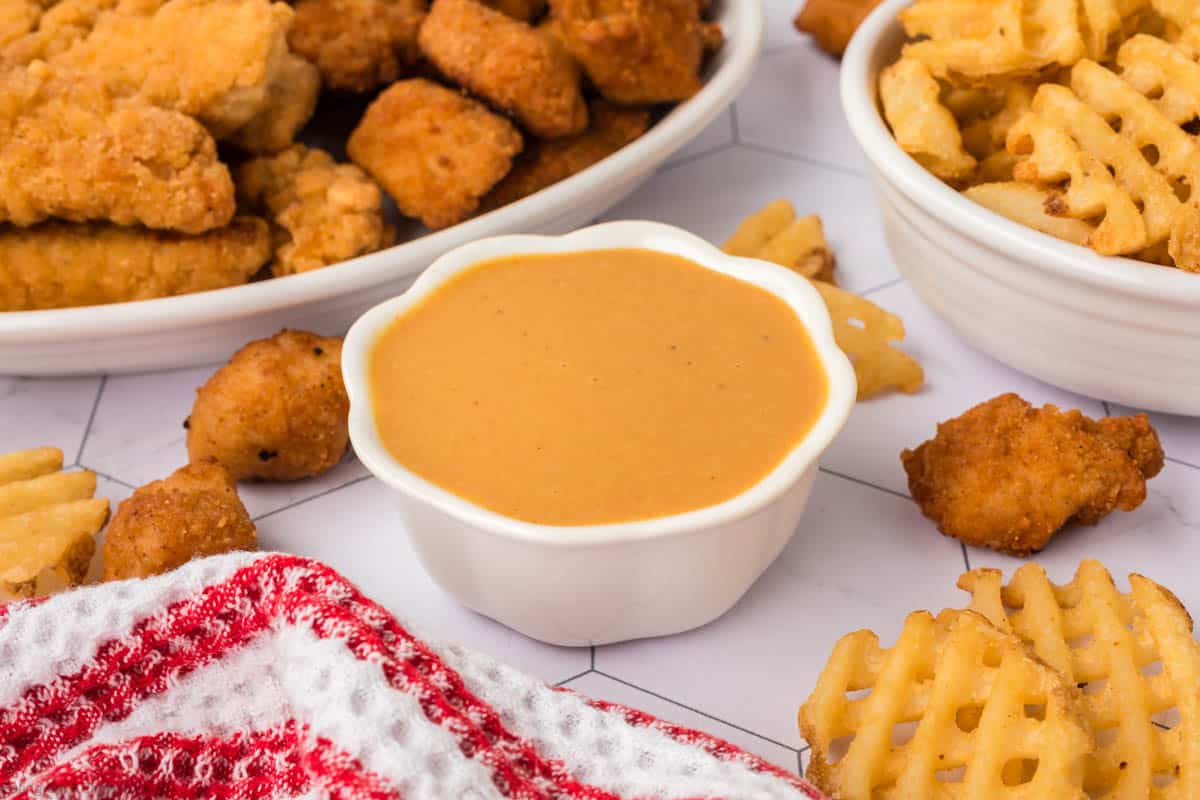 Chick Fil A Sauce in a white bowl with chicken nuggets and fries on the side