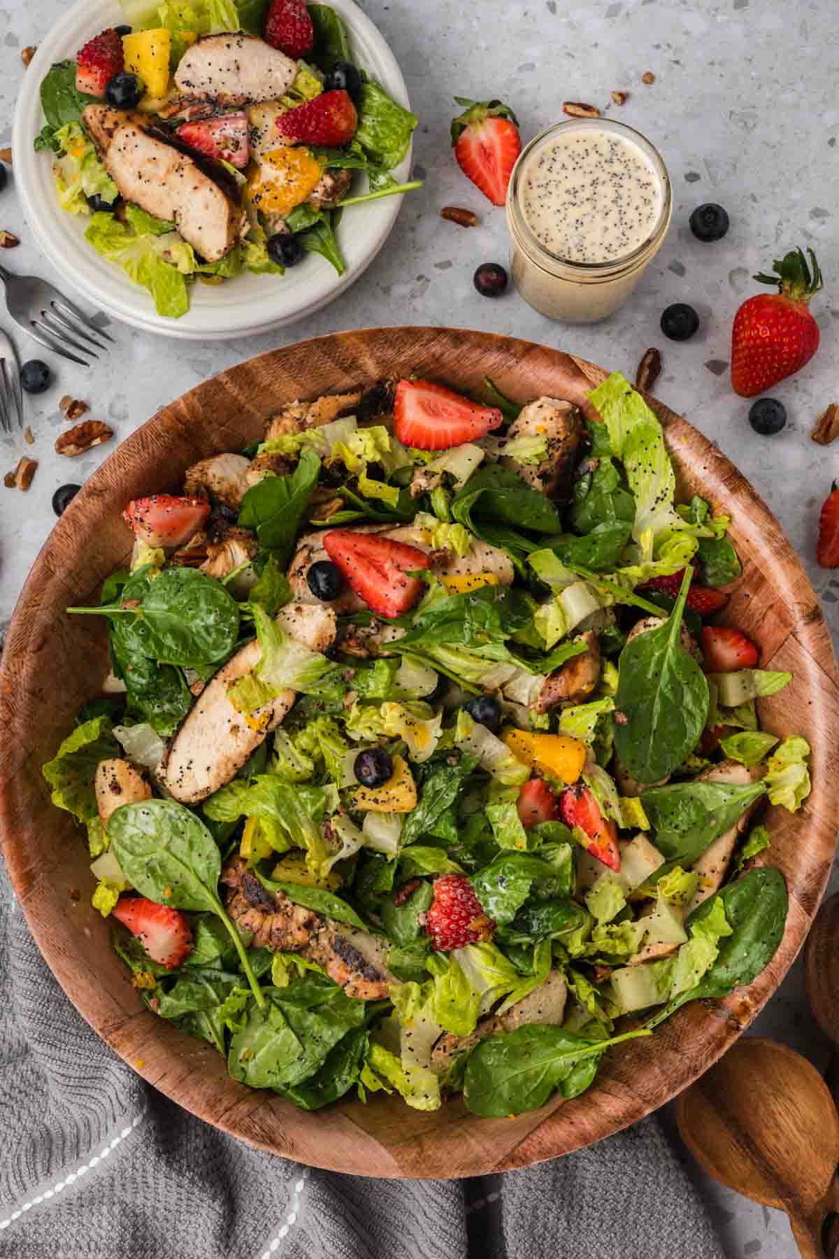 Strawberry Poppyseed Salad in a large bowl topped with slices of grilled chicken, slice strawberries, blueberries and oranges