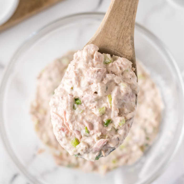 Tuna Salad mixed in a bowl with a serving on a wooden spoon