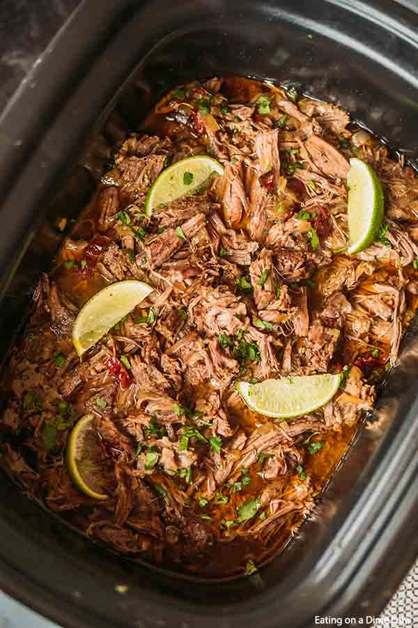 Close up image of Barbacoa Beef in the crock pot with lime on top. 