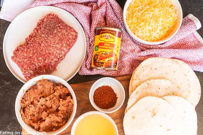 Ingredients needed to make mexican pizza - beef, taco seasoning, water, veg oil, tortillas, refried beans, red enchilada sauce, cheese, tomato, green onions, and black olives. 