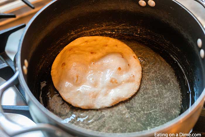 Close up image of tortilla being fried in a skillet. 