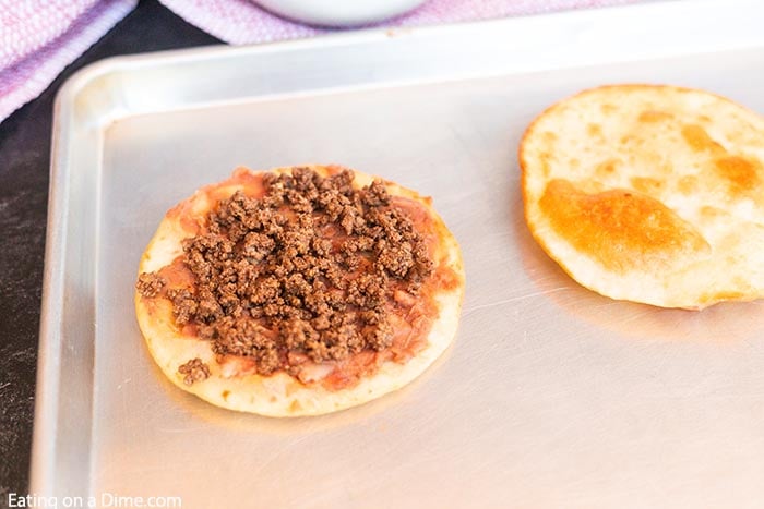 Topping the crispy tortilla with refried beans and cooked ground beef