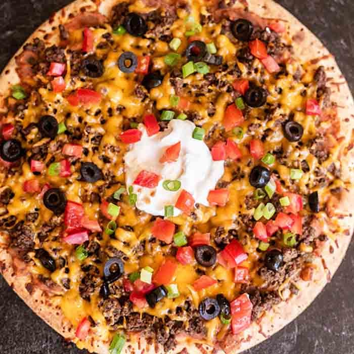 Our family loves this Taco pizza recipe with pizza crust and it is so easy to prepare. This easy homemade Mexican pizza with refried beans is loaded with so much flavor and tons of delicious toppings. #eatingonadime #tacopizzarecipe