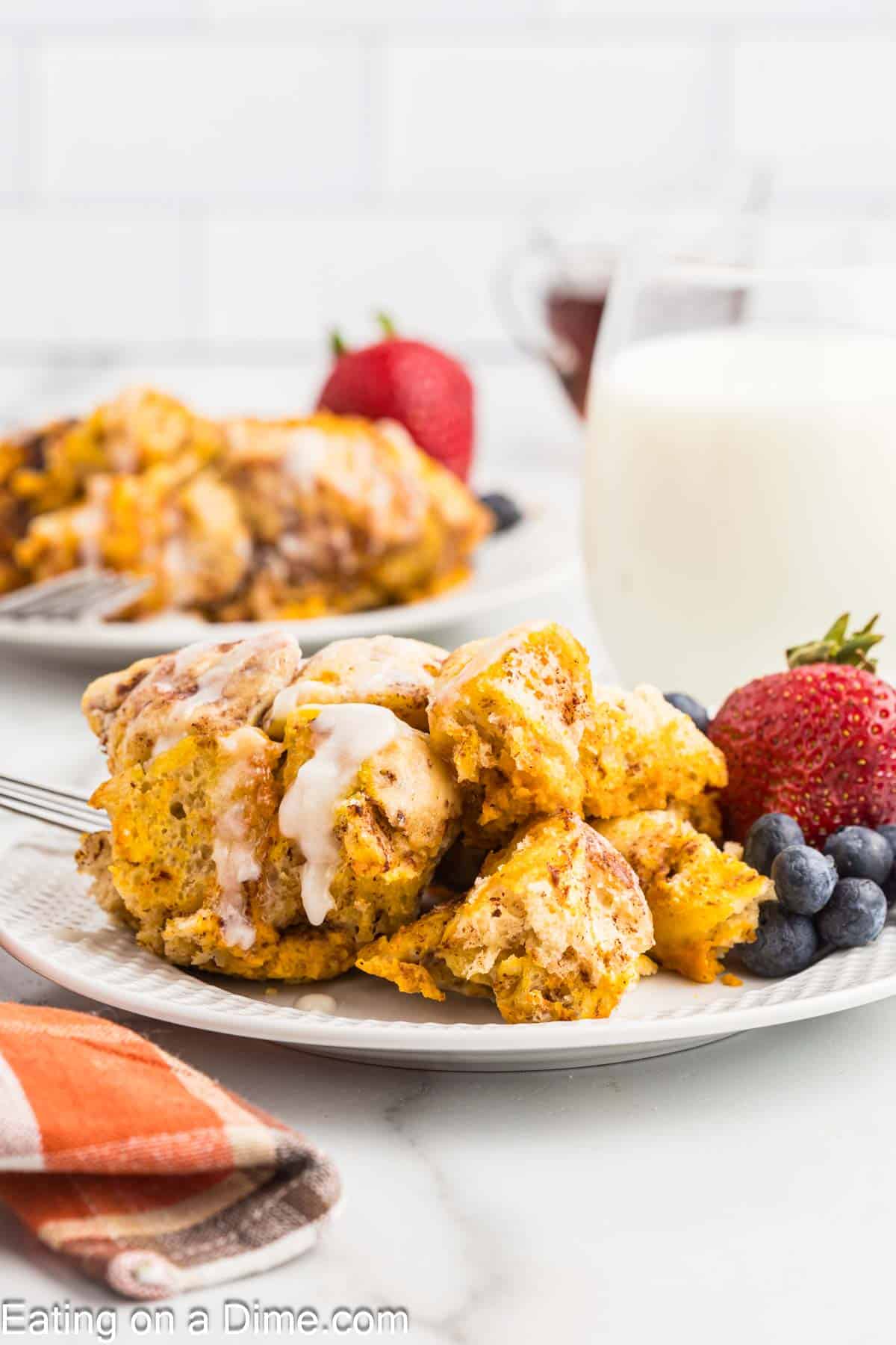Pumpkin Cinnamon Roll Casserole serving on a plate with fresh blueberries and strawberries
