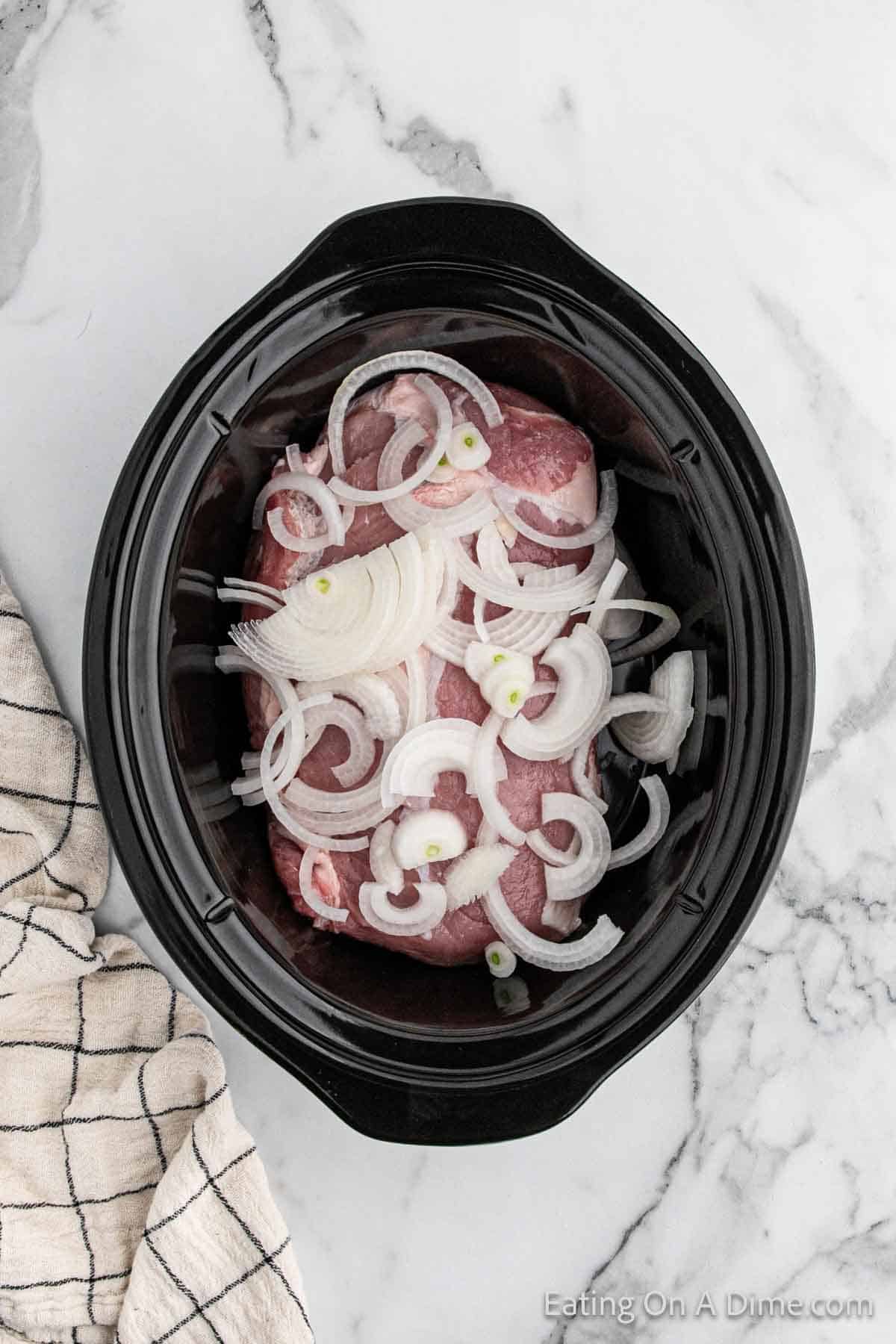 Topping the pork loin with onions in the slow cooker