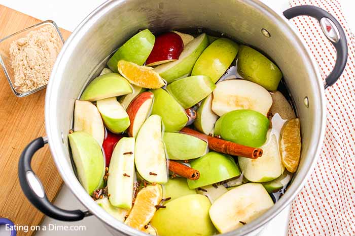 Adding water and seasoning to the fruit in the large pot. 
