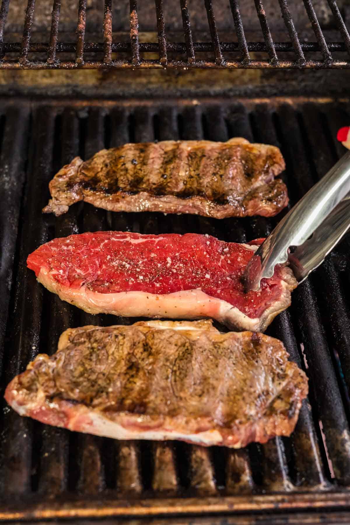 Steak on the grill being flipped after cooking one side