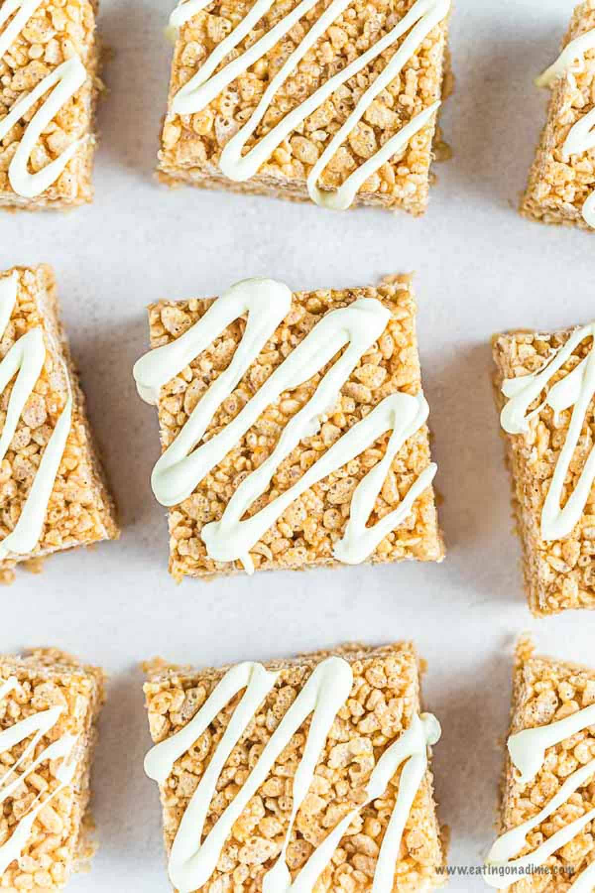 Pumpkin Rice Krispie Treats laid out on a board drizzled with frosting on top.  