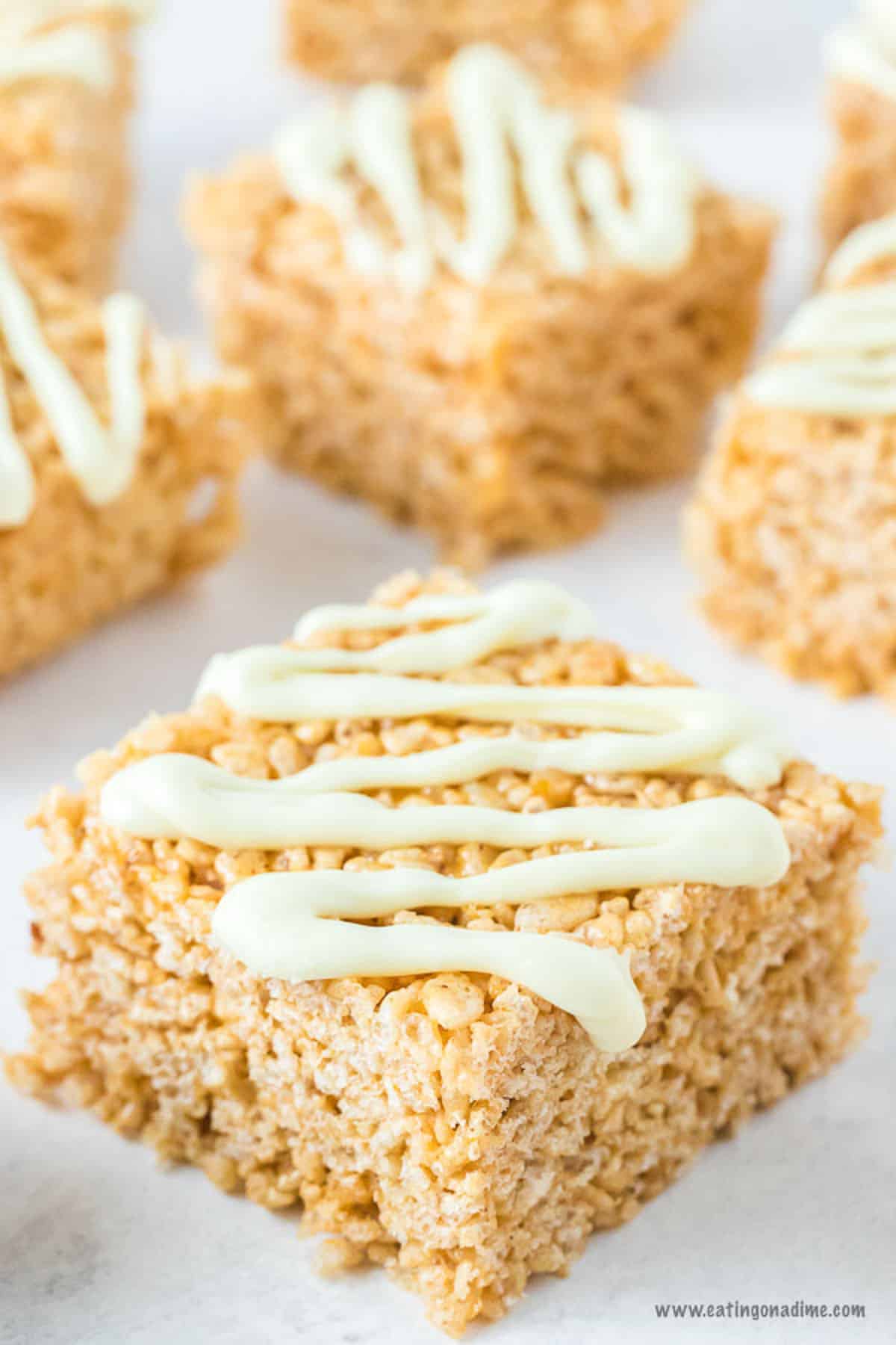 Pumpkin Rice Krispie Treats laid out on a board drizzled with frosting on top.  