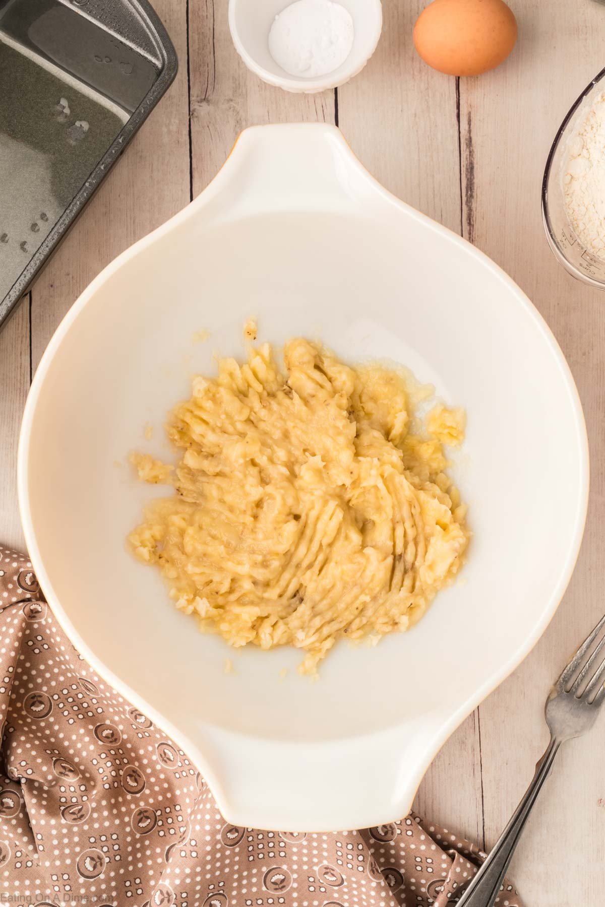 Mashing bananas in a white bowl