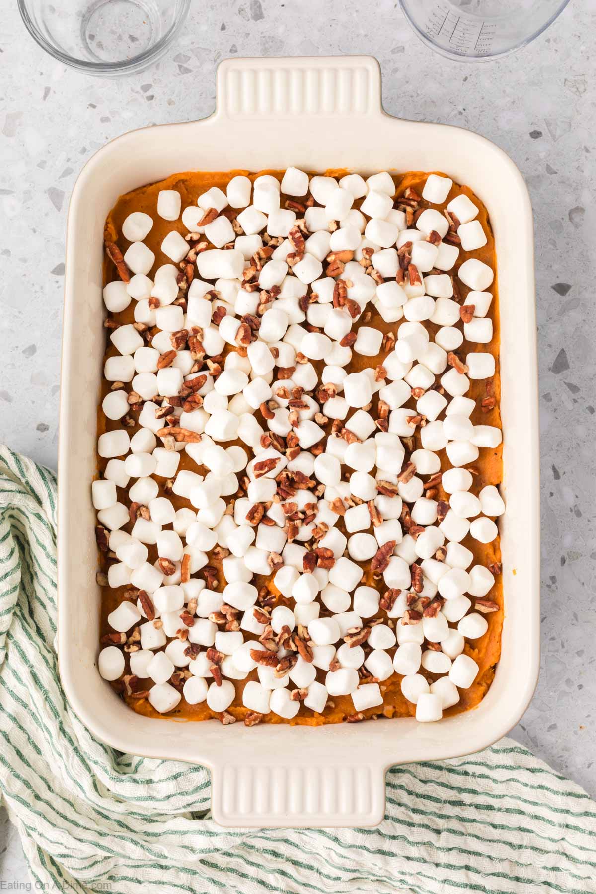 Topping the mashed sweet potatoes with pecans and marshmallows