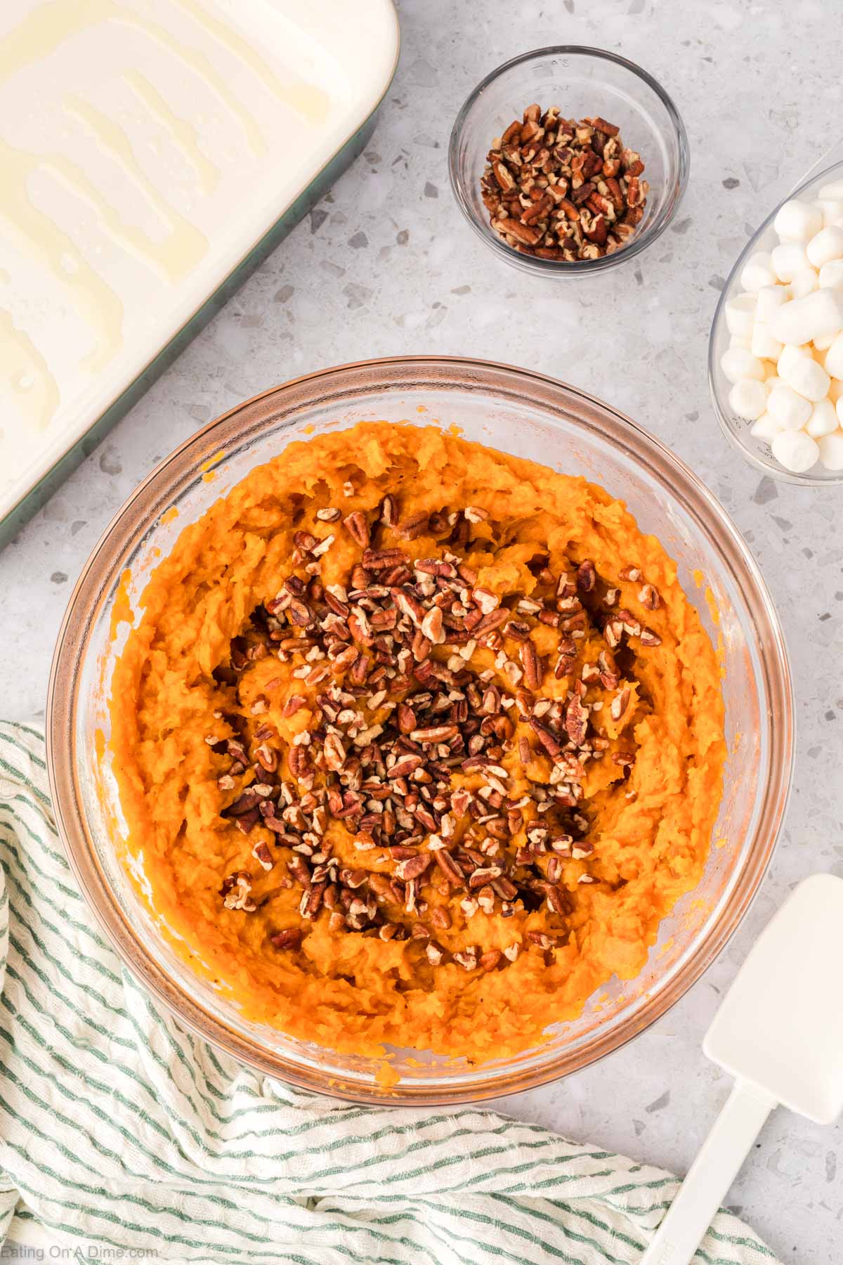 Mashed sweet potatoes in a bowl with chopped pecans