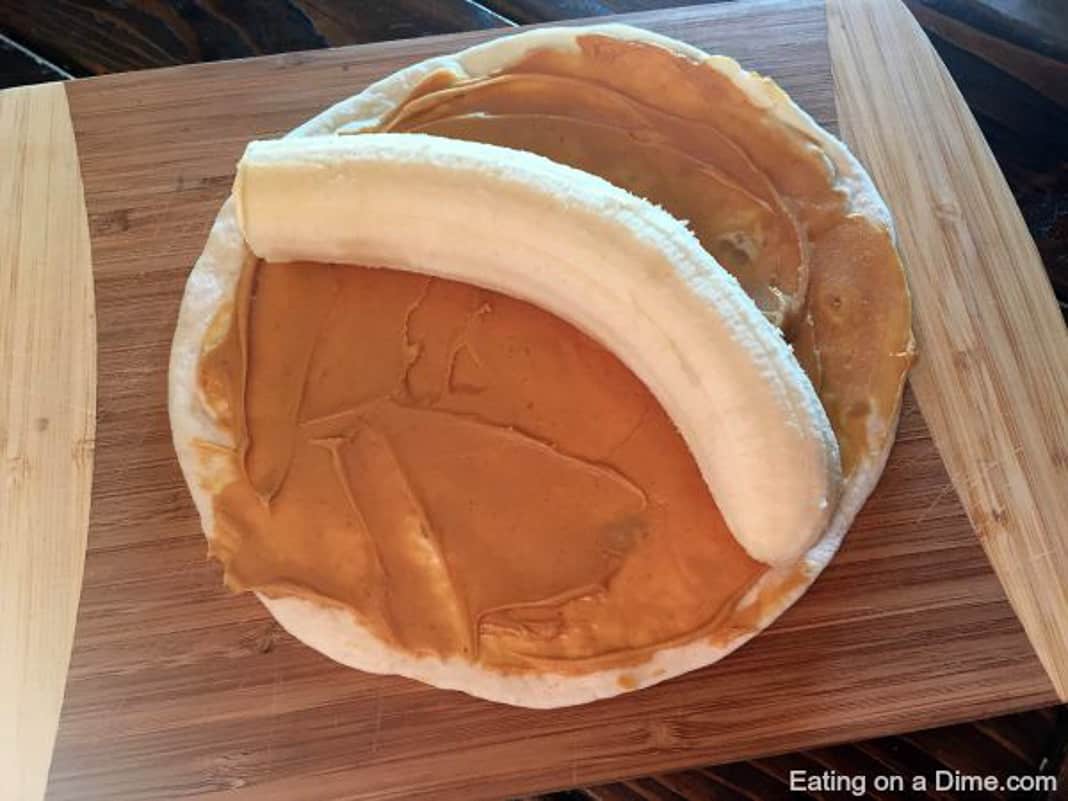 Banana placed on a tortilla with peanut butter on top