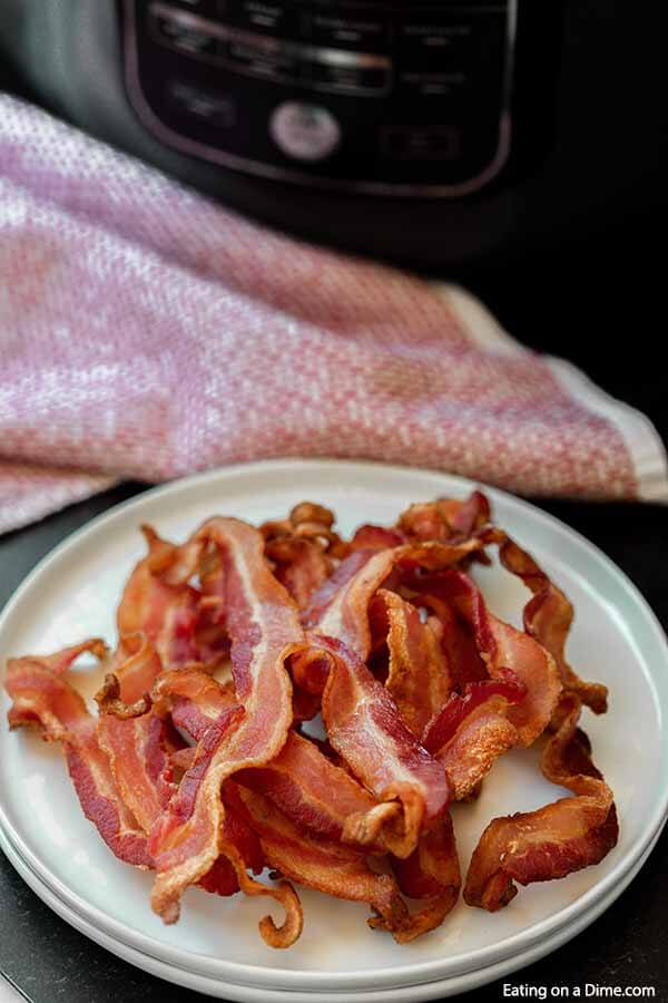 Air fryer bacon recipe takes just minutes to make and you can enjoy crispy and delicious bacon. Gone are the days of standing over a hot stove frying bacon! Learn how to make bacon in air fryer. #eatingonadime #airfryerbacon 