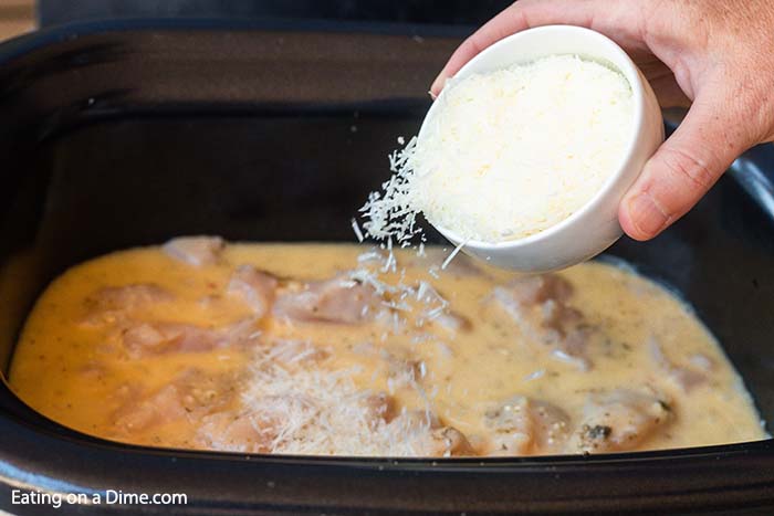 Parmesan cheese being added to a crock pot. 