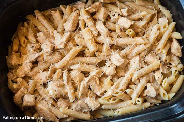 A crock pot full of this Creamy Alfredo Olive Garden Chicken Pasta in a large crock pot topped with parmesan cheese.  