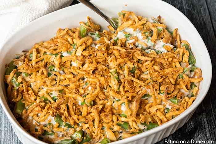 Close up image of green bean casserole in a white dish with a serving spoon. 