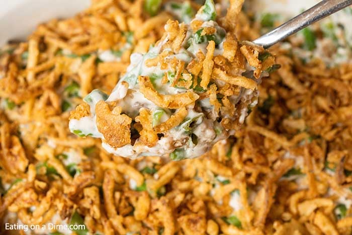 Close up image of green bean casserole with a silver serving spoon. 
