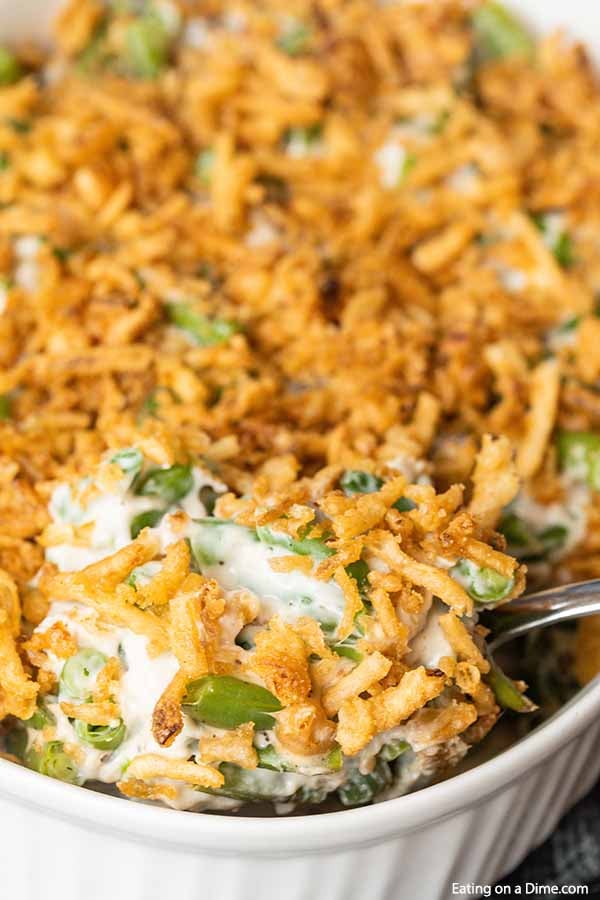 Close up image of green bean casserole with a silver spoon. 