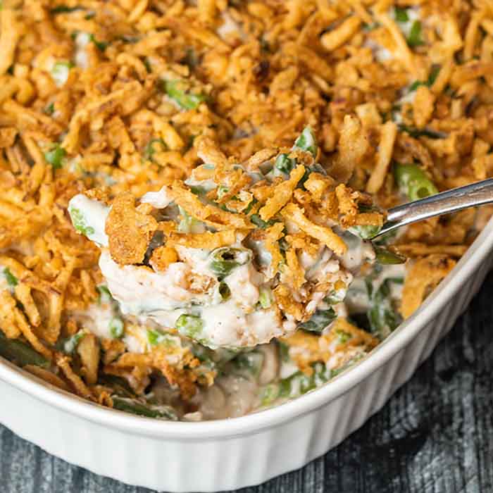 Close up image of green bean casserole with a serving spoon. 